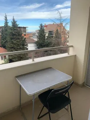 a table and a chair on a balcony with a window at Pazardzhik suite home in Pazardzhik