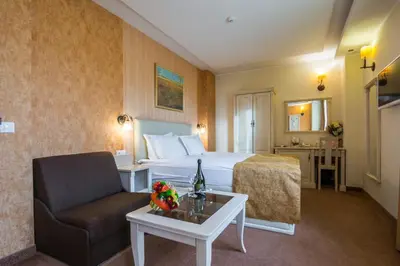 a hotel room with a bed and a chair and a table at Hotel Adria in Sofia