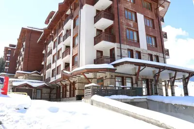 a building with snow on the ground in front of it at Panorama Bansko in Bansko