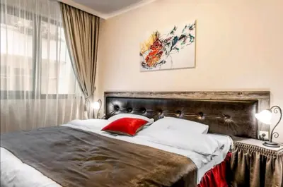 a bedroom with a large bed with a red pillow at Astrea Deluxe in Hisarya