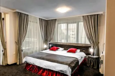 a hotel room with a large bed with red pillows at Astrea Deluxe in Hisarya