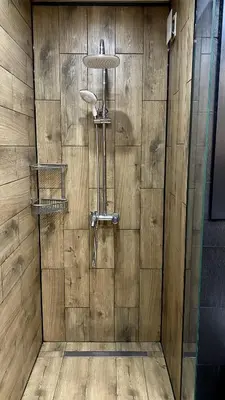 a shower in a bathroom with a wooden wall at Deluxe Studio 200m from Ski Road in Bansko