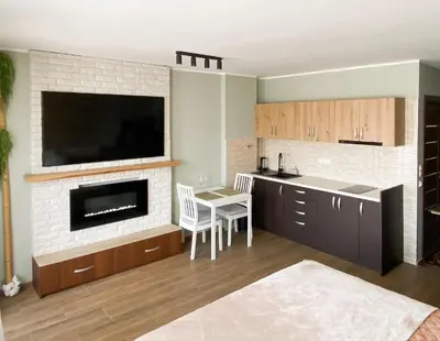a kitchen with a fireplace and a table and a tv at Deluxe Studio 200m from Ski Road in Bansko