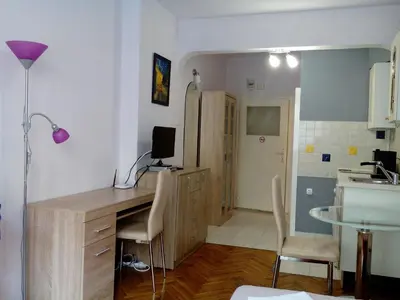 a room with a desk with chairs and a kitchen at Studio Rositza in Sofia