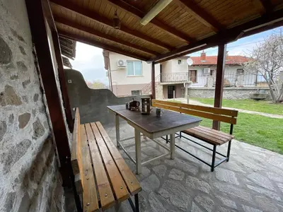 a patio with a wooden table and a bench at Еделвайс Edelvais in Kostenets Village