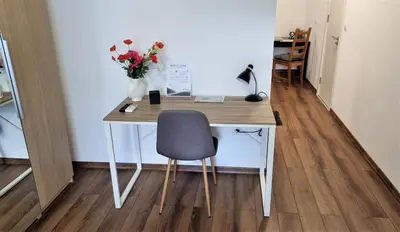 a desk with a chair and a vase of flowers at Luxury Quiet Apartment in the City Center in Plovdiv