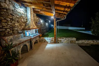 an outdoor patio at night with a stone wall at Къща за приятели Недкови in Vasil Levski