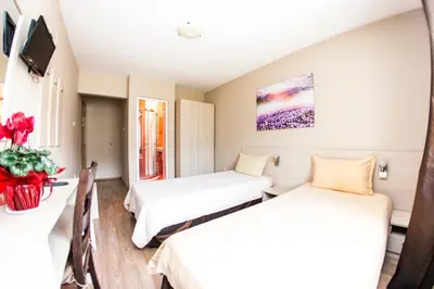 two beds in a room with a table and a tv at Family Hotel Madrid in Sofia