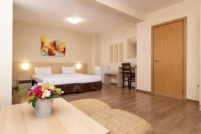 a hotel room with a bed and a table with flowers at Family Hotel Madrid in Sofia