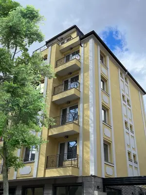 a tall yellow building with balconies and a tree at COOP Apartments, Sofia - Free Parking in Sofia
