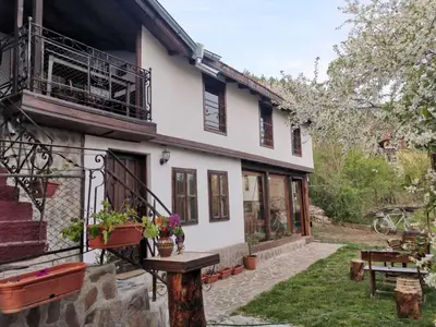 a white house with a table in the yard at Къща за гости Старата череша село Раждавица in Rzhdavitsa