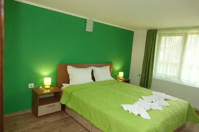 a green bedroom with a bed with towels on it at Горски Кът in Devin