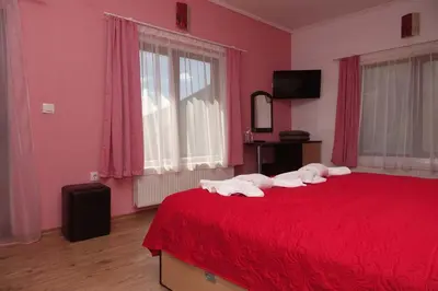 a bedroom with a red bed with towels on it at Горски Кът in Devin