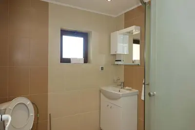 a bathroom with a sink and a toilet and a window at Горски Кът in Devin