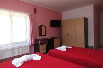 a bedroom with two beds with red sheets and a window at Горски Кът in Devin