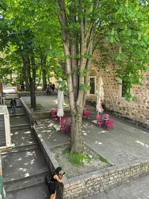 a woman taking a picture of a tree and tables and chairs at 4 Rooms in Plovdiv