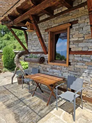 a wooden table and chairs in front of a stone building at Leshten Valentin's House in Leshten