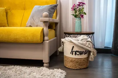 a yellow couch and a basket with a vase of flowers at Какао Апартамент Велинград in Velingrad