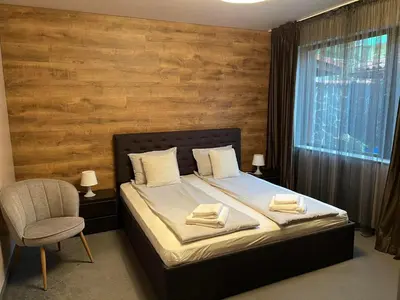 a bedroom with a bed and a chair and a window at Guest House EGO in Bratsigovo