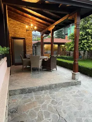 a patio with a table and chairs under a pergola at Guest House EGO in Bratsigovo