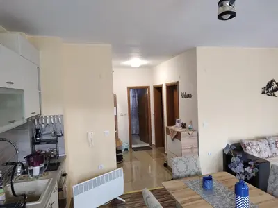 a kitchen and a living room with a table at Апартамент за гости Виктория in Chepelare