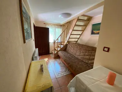 a living room with a couch and a stair case at Белевската къща с беседка Belevska House with gazebo in Smolyan