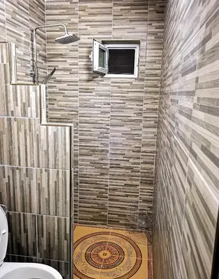 a bathroom with a shower with a toilet and a window at Студио за гости - Лили in Ognyanovo