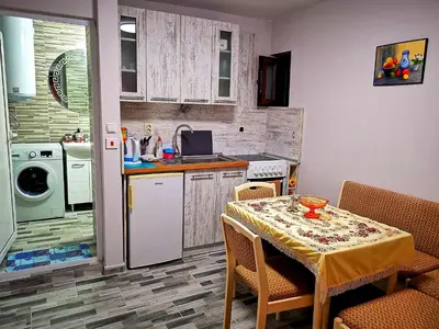 a kitchen with a table and a kitchen with a table and chairs at Студио за гости - Лили in Ognyanovo