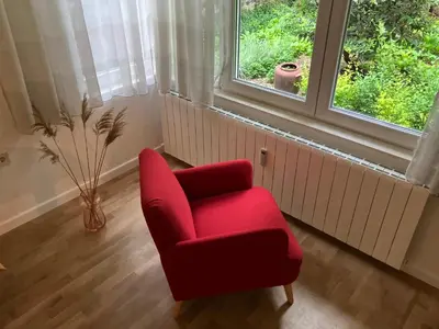 a red chair in a room with a window at Opera Flat in Sofia