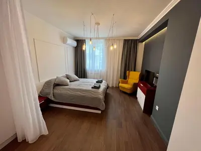 a bedroom with a bed and a yellow chair at LOCATION ! LOCATION ! LOCATION ! City Garden View Apartment in Sofia