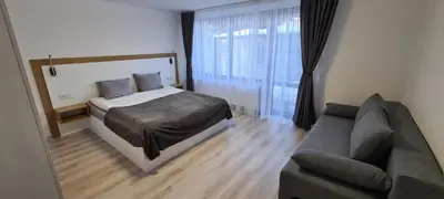 a bedroom with a bed and a couch at Апартаменти Сънрайс Чепеларе in Chepelare