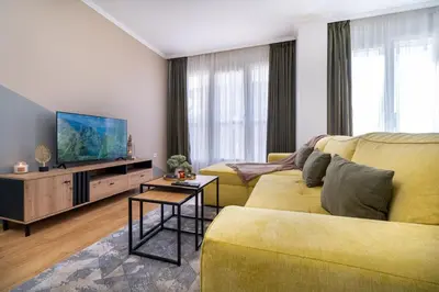 a living room with a yellow couch and a flat screen tv at Modern & Elegant City Center Apartments in Plovdiv