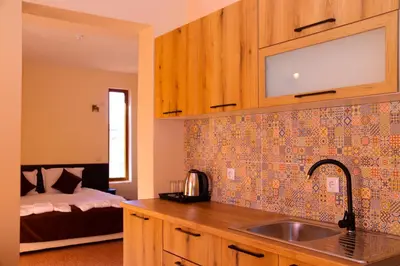 a kitchen with a sink and a bedroom with a bed at Семеен хотел Света Марина in Dobrinishte