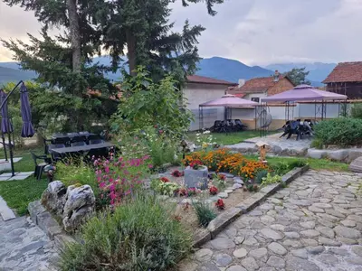 a garden with flowers and a bench in a yard at Семеен хотел Света Марина in Dobrinishte