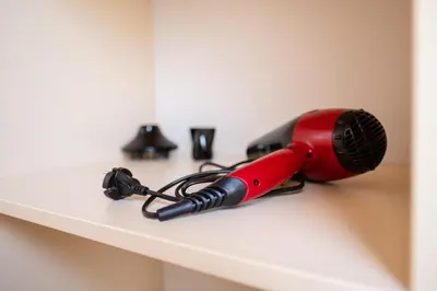 a red hair dryer sitting on a shelf at Spacious apartment in the city center in Plovdiv