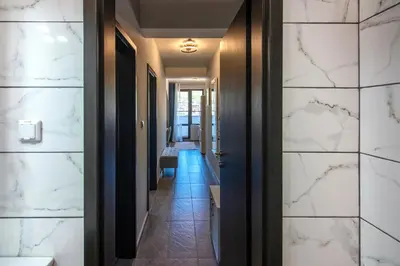 a corridor of a hotel with white marble walls at Мансарда с фантастични гледки и две спални in Chepelare