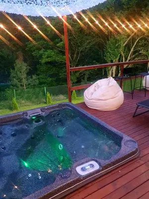 a hot tub on a wooden deck with an umbrella at Green View 1 in Skrino
