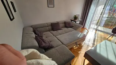 a living room with a couch and a large window at Urban Comfort 1BR near South Park with Balcony in Sofia