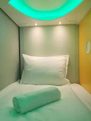 a bed with a blue towel on top of it at Green Cube Capsule Hostel in Sofia