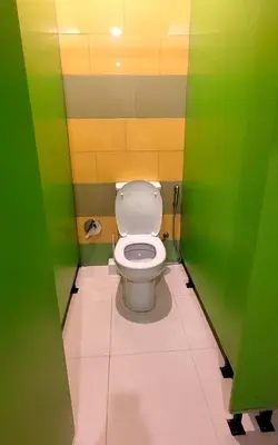 a bathroom with a toilet with green and yellow walls at Green Cube Capsule Hostel in Sofia