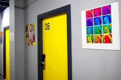 a yellow door in a hallway with paintings on the wall at Green Cube Capsule Hostel in Sofia