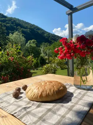 a loaf of bread on a table with a vase of flowers at Къща за гости Остриля in Cherni Vit