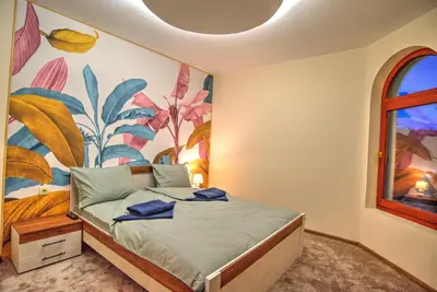 a bedroom with a bed with a painting on the wall at Вила Форте Villa Forte in Pamporovo