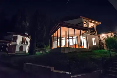 a house with a lot of glass windows at night at Вила Форте Villa Forte in Pamporovo