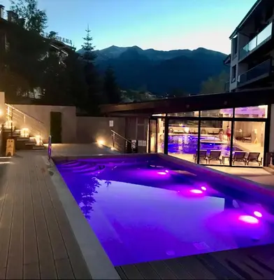 a swimming pool lit up at night with purple lights at Luxury SPA Apartments TOP resort Bansko - incl wellness in Bansko