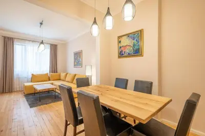 a dining room and living room with a wooden table and chairs at Gorgeous 2 BDRM fully equipped flat, TOP location in Sofia