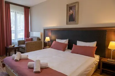 a hotel room with a large bed and a chair at Апартамент и Студия 