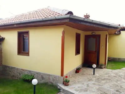 a small yellow house with a brown door at Sarafova Guest House in Koprivshtitsa