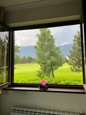 a window with a clock and a view of a field at The Nature View Suite, part of Terra Complex & Spa in Bansko