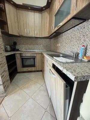 a kitchen with wooden cabinets and a sink at Лукс апартамент Базилика отделен вход in Sandanski